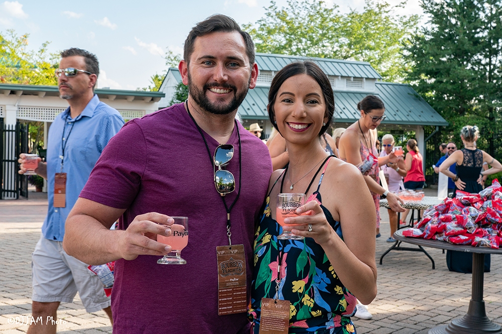 man and woman holding bourbon smiling at the camera